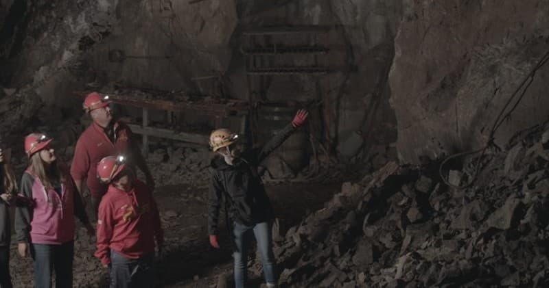 Guided historic mine tour underground with interpretive guide pointing