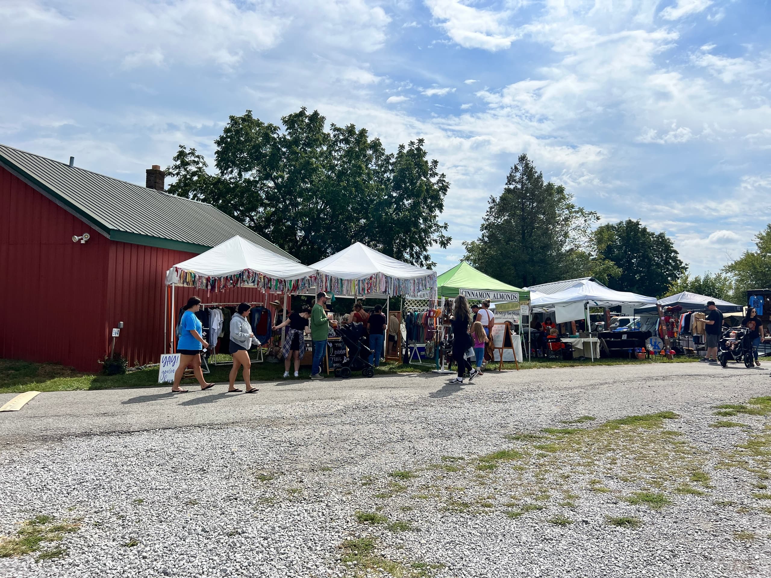 Farm market tents and red barn with visitors on sunny farm day