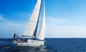Sailboat cruising on open ocean under blue sky, coastal sailing