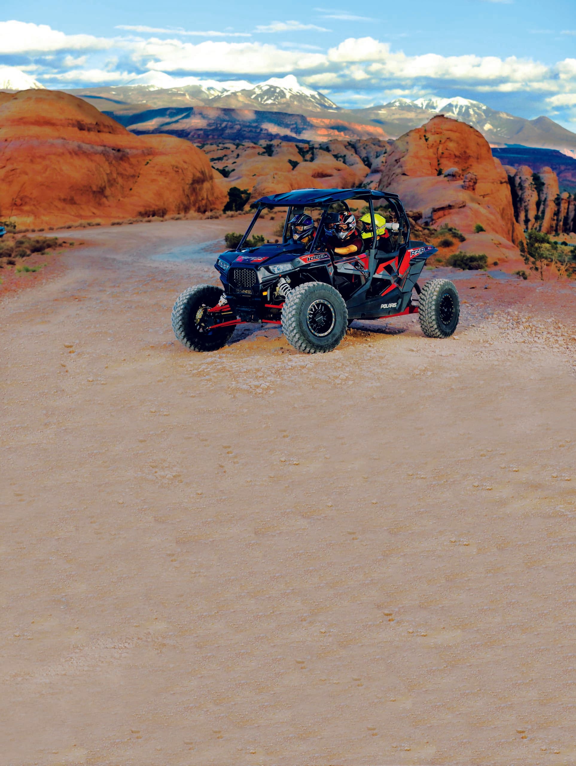 High-speed ATV racing across sandy canyon with distant mountain views
