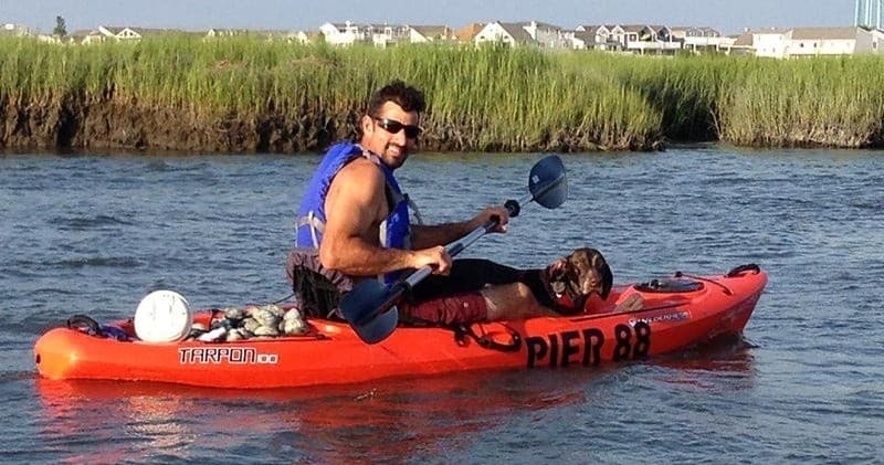 Solo kayaker paddling near coastal marshes with Pier 88