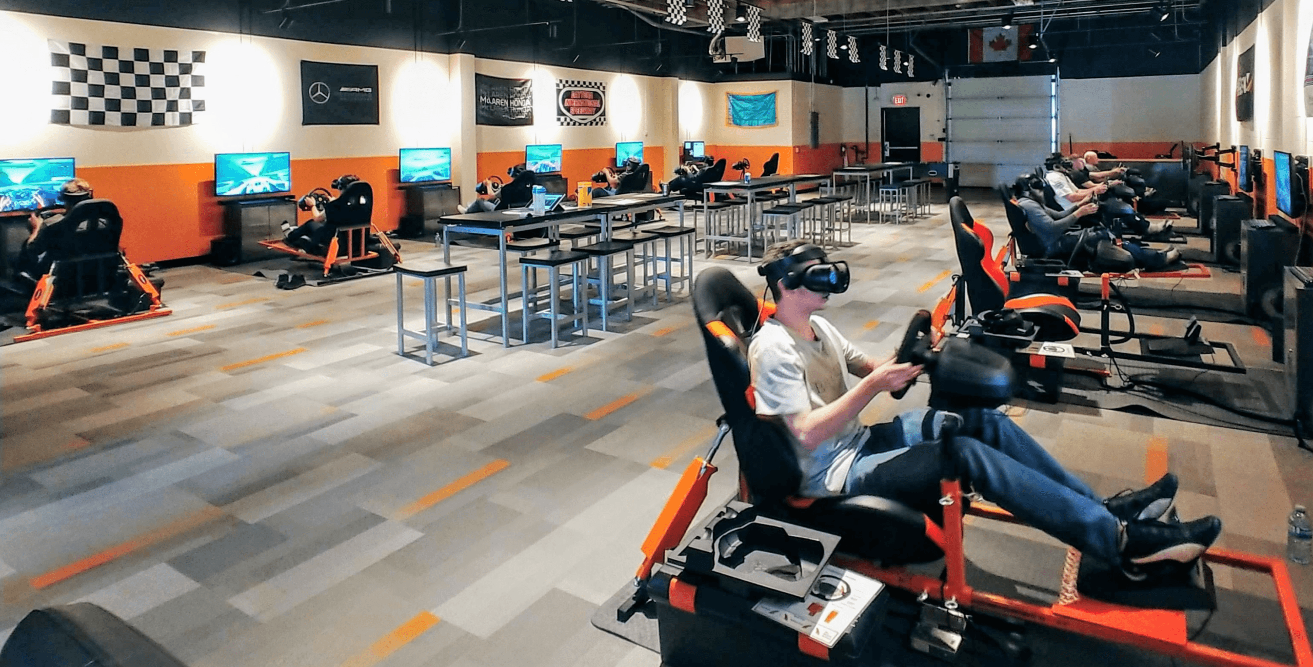 Customers using VR racing simulators in a spacious arcade