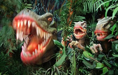 Animatronic dinosaurs snarling in indoor jungle theme-park ride