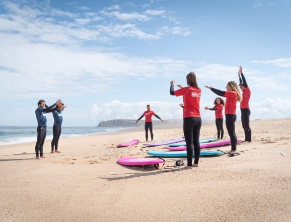 Surf lesson group practicing on sandy Atlantic beach with surfboards