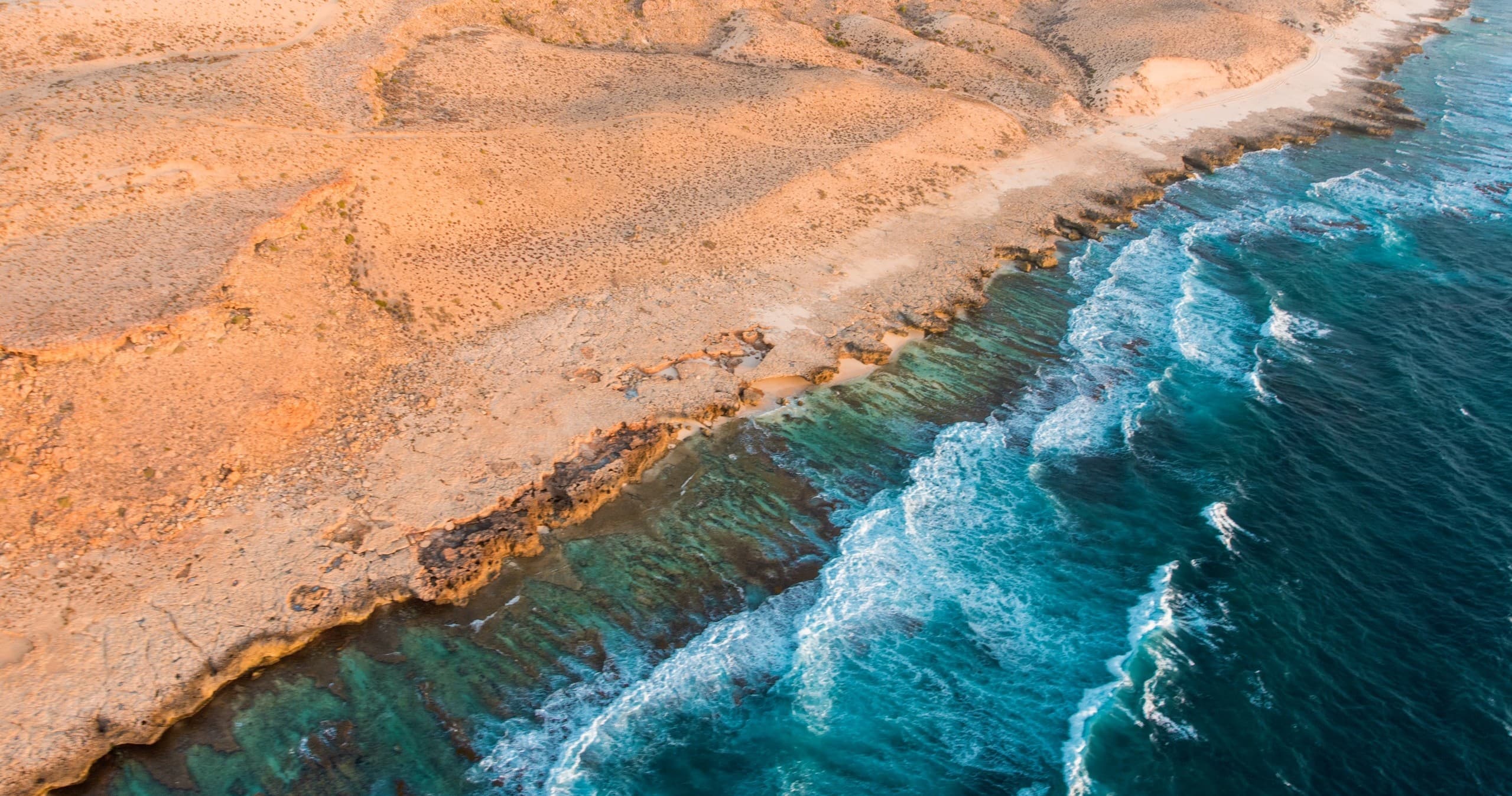 Coastal aerial shot of turquoise surf and red cliffs, Coral Coast