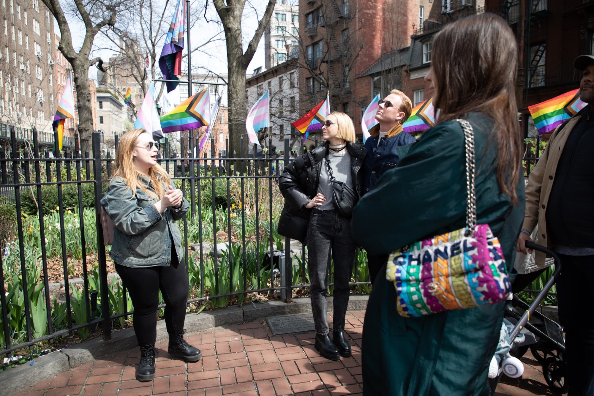 Guided walking tour group in city park with rainbow flags