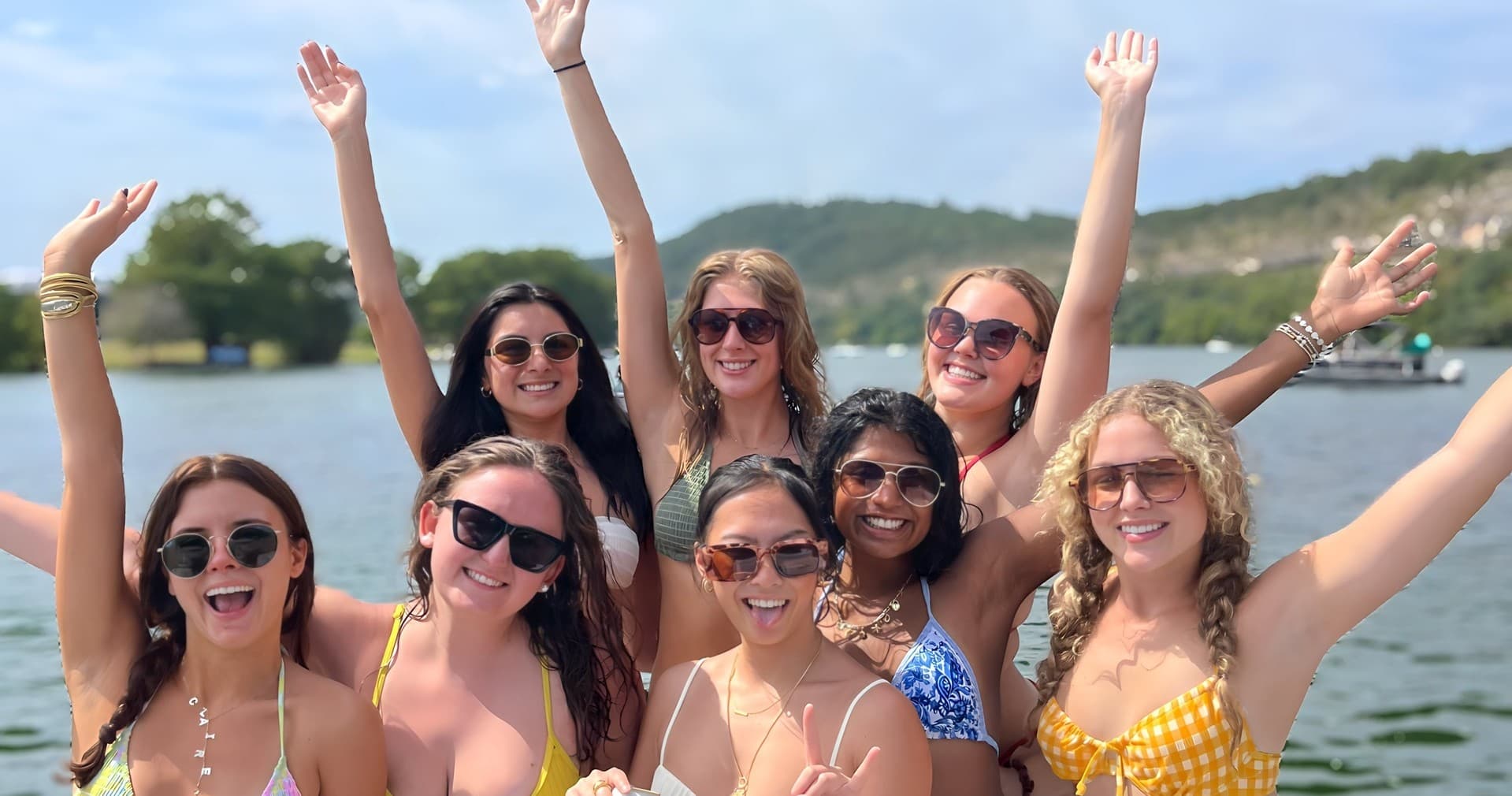 Friends cheering in swimsuits on lake pontoon boat afternoon