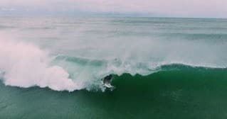 Powerful green ocean wave breaking into a surf barrel