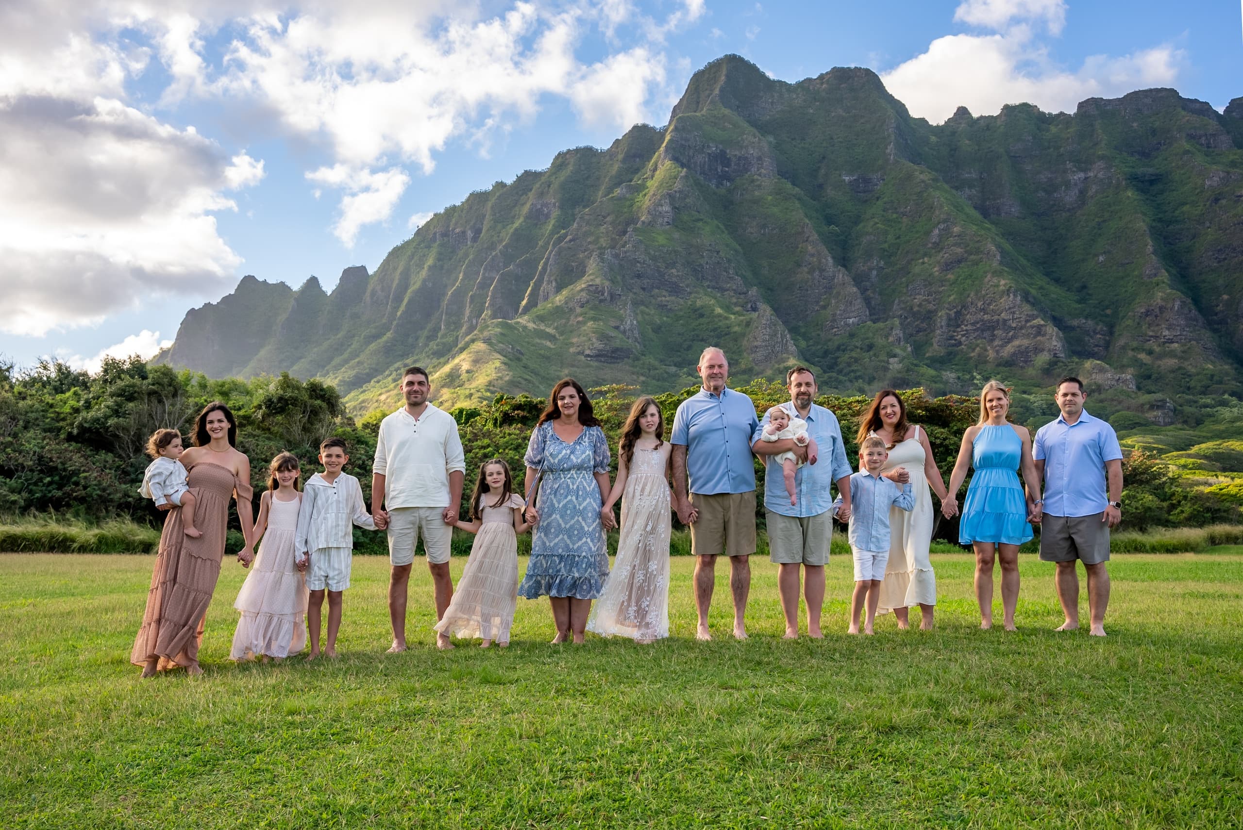 Extended family posing on grassy lawn with mountain vista