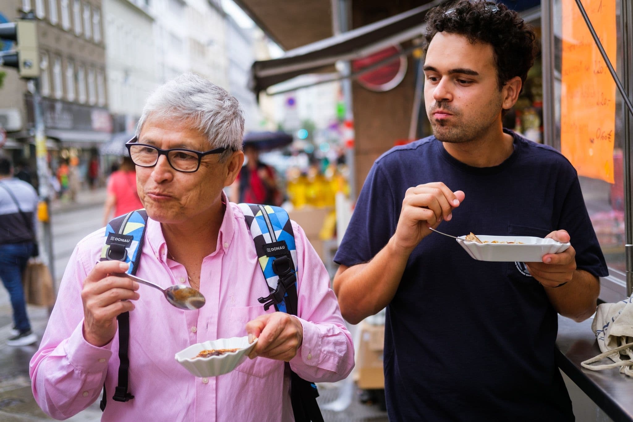 Two travelers eating street food on vibrant city walking tour