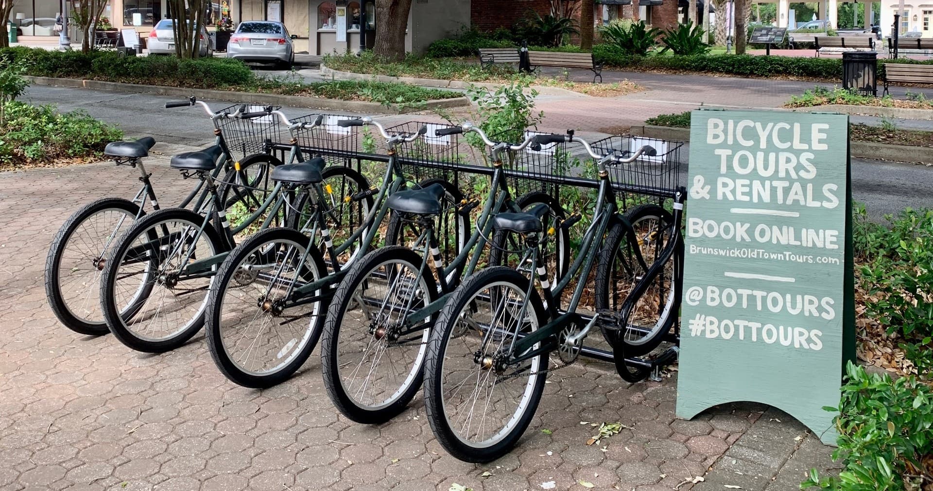 Row of rental bicycles with 'Bicycle Tours & Rentals' sign on plaza