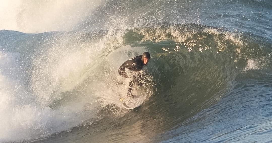 Surfer barreling inside a dramatic ocean tube wave at shore