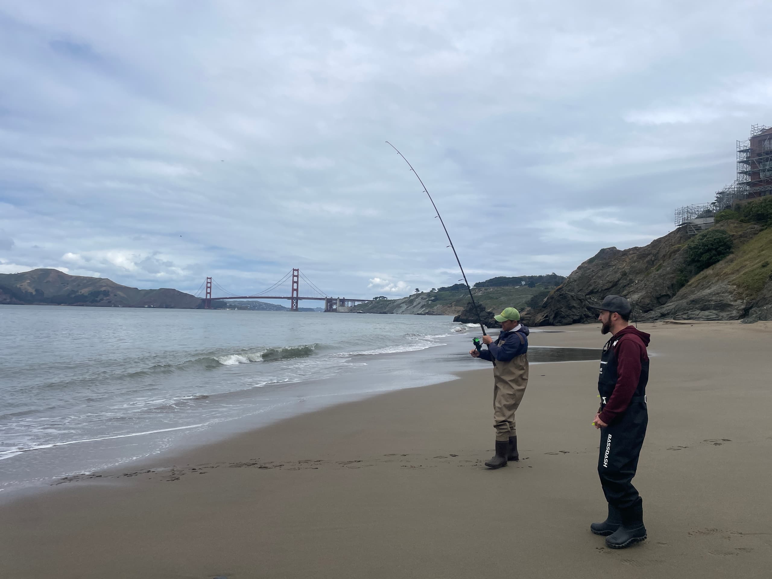 Anglers surf fishing on San Francisco beach with Golden Gate