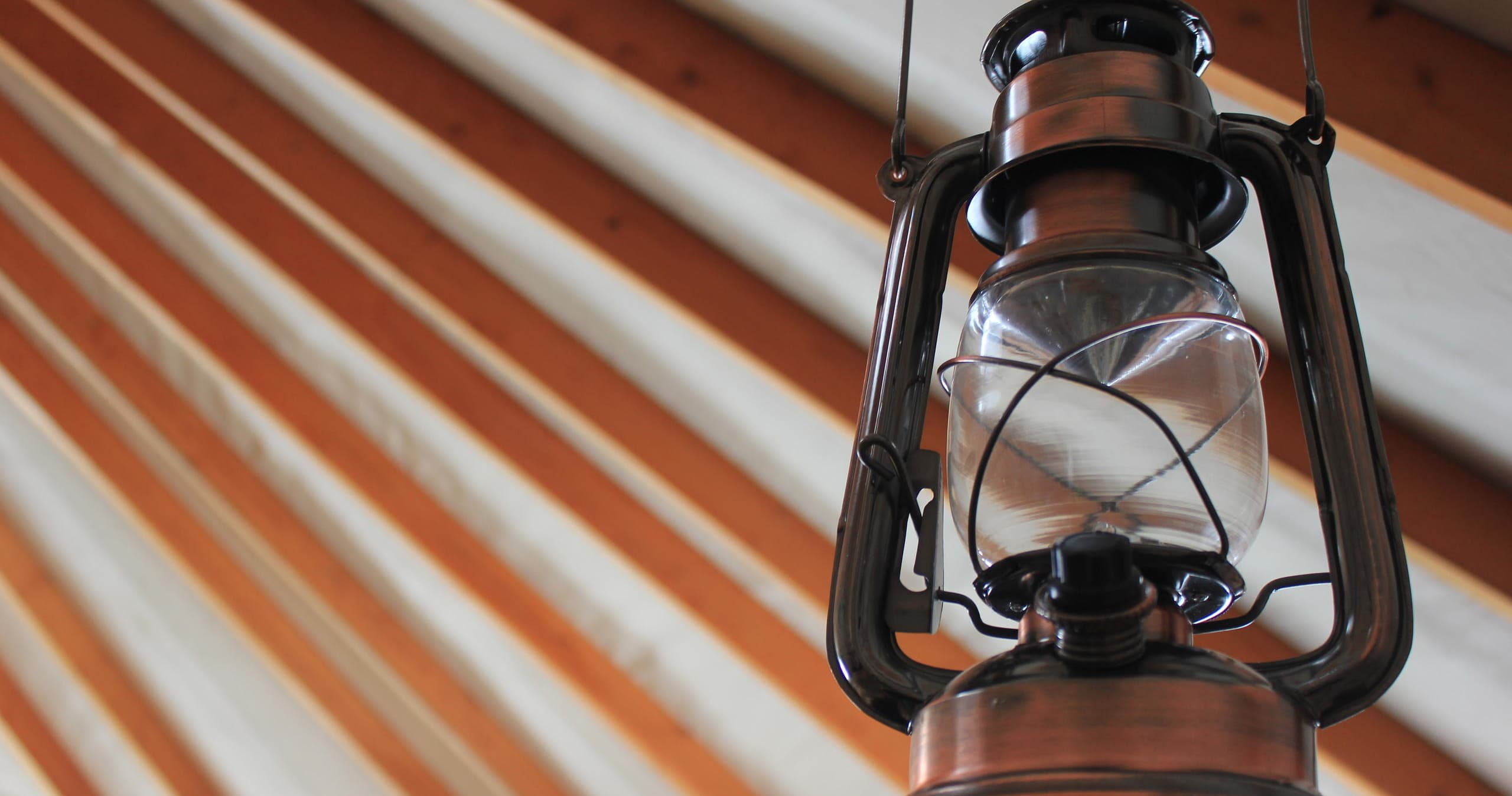 Rustic oil lantern hanging inside yurt interior with rafters