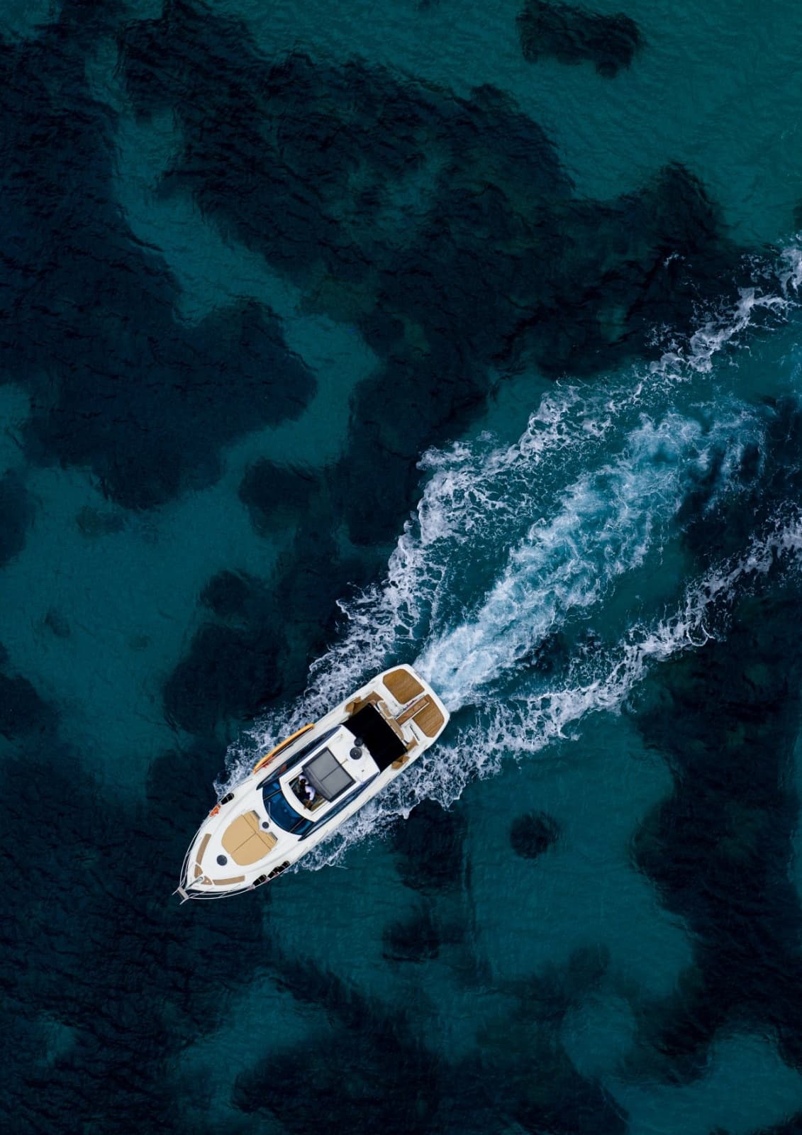Aerial view of yacht sailing over clear blue coastal waters