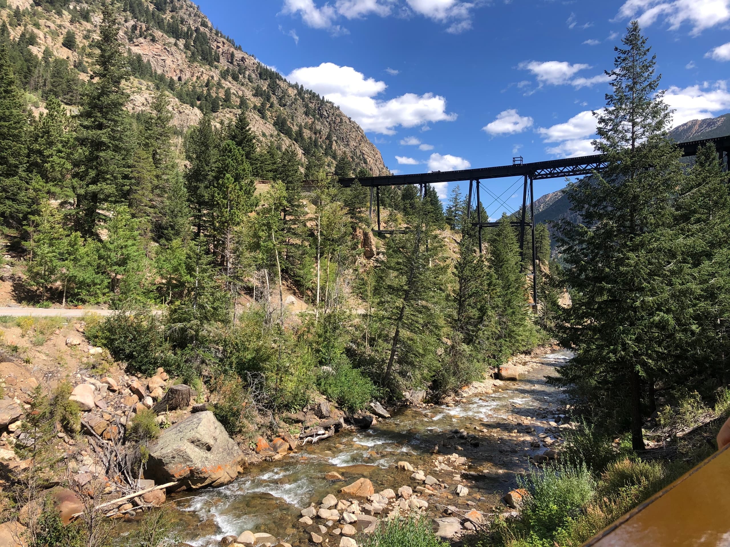 Mountain canyon with river and rail bridge, riverside hike