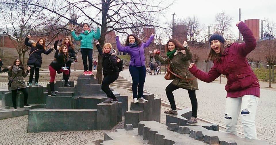 Tour group jumping on public steps in urban park walking tour