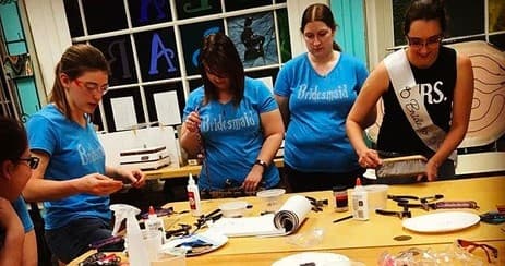 Group of students crafting stained glass panels in indoor studio class