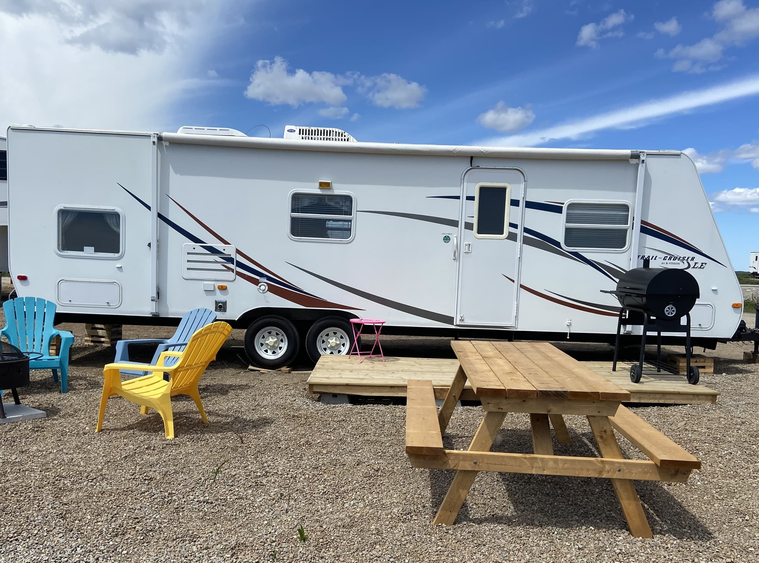 Travel trailer with picnic table and Adirondack chairs