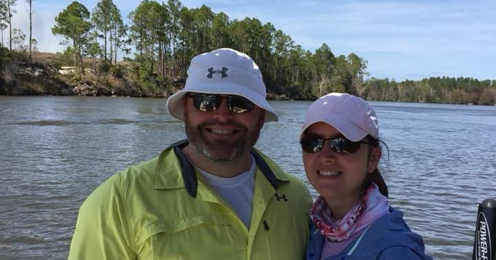 Couple on boat enjoying coastal estuary fishing trip with trees