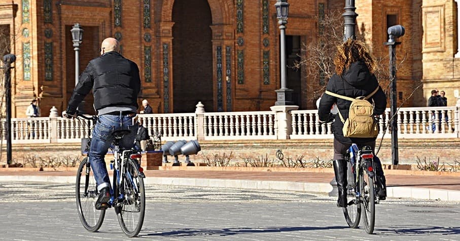 Cyclists on urban bike tour past Plaza de España, Seville