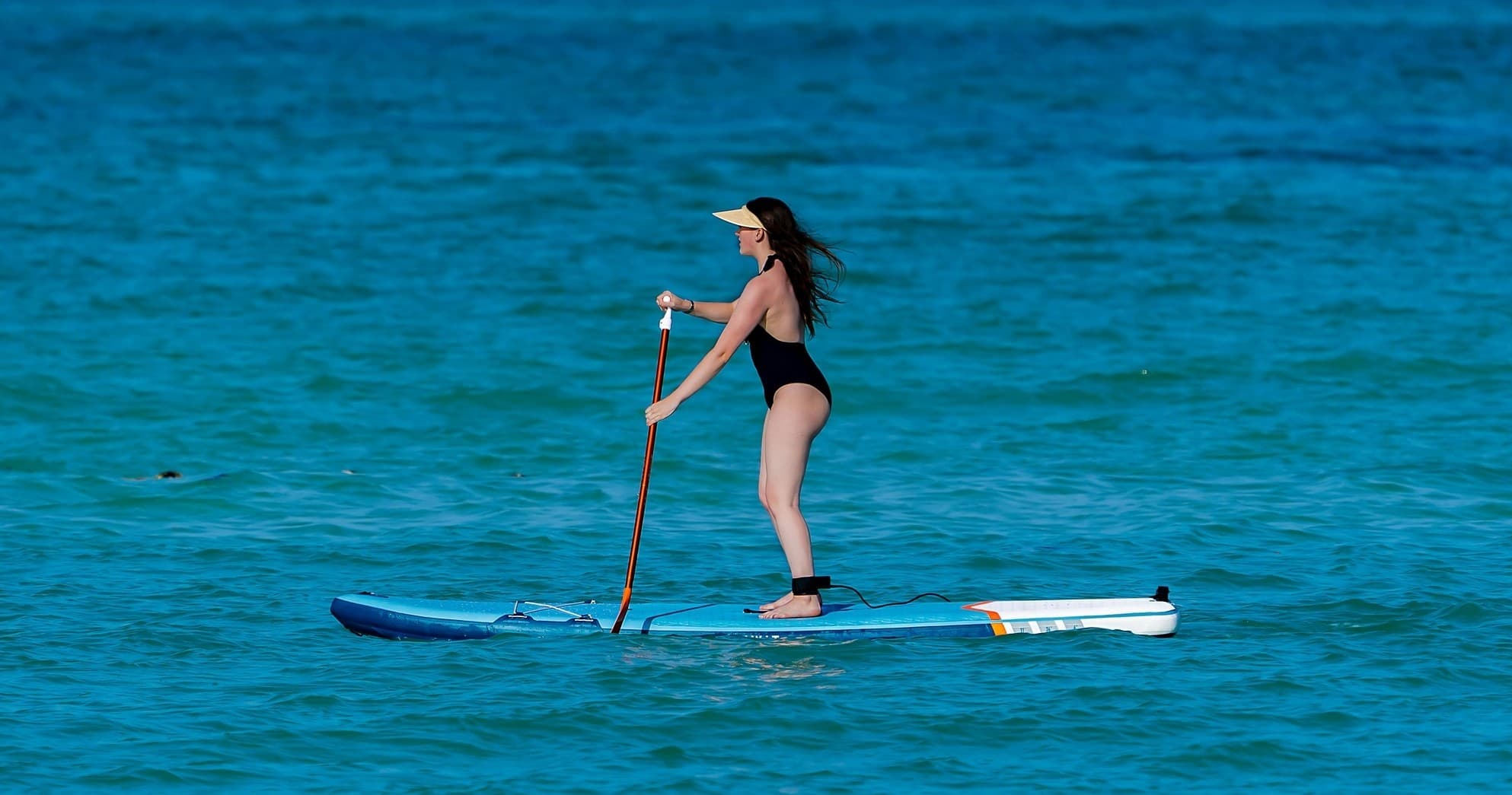 Stand-up paddleboarding on turquoise ocean near tropical beach