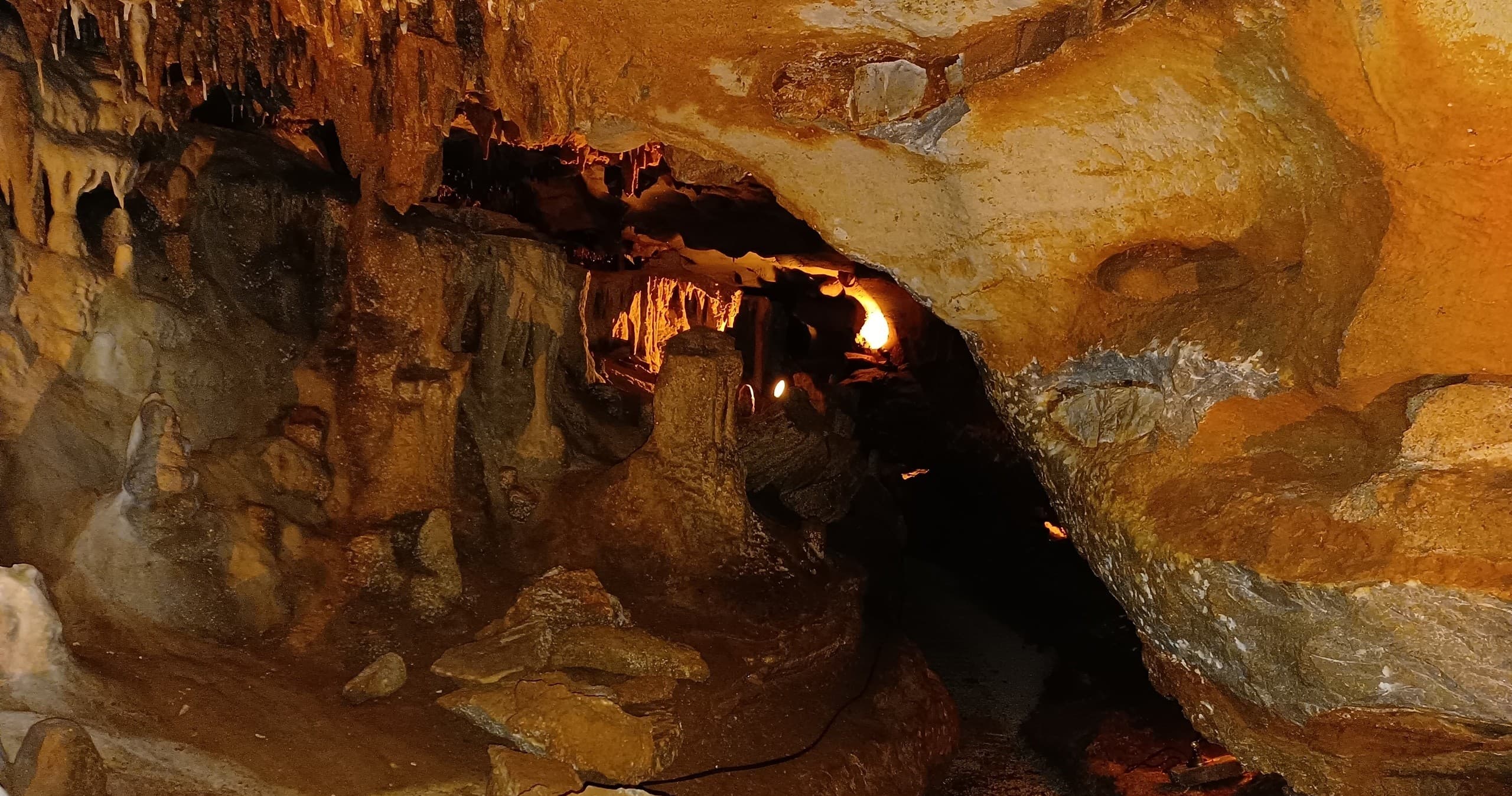 Narrow illuminated cave tunnel leading deeper, spelunking passage