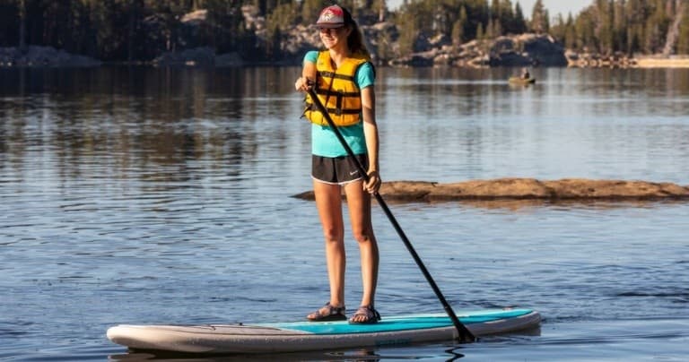 Stand-up paddleboarder cruising on calm freshwater lake