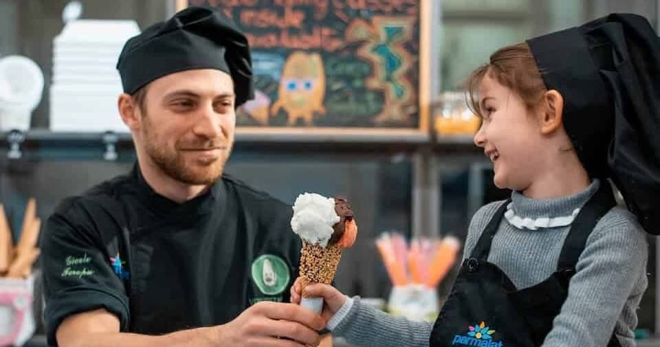 Gelato chef serving ice cream cone to child in shop interaction