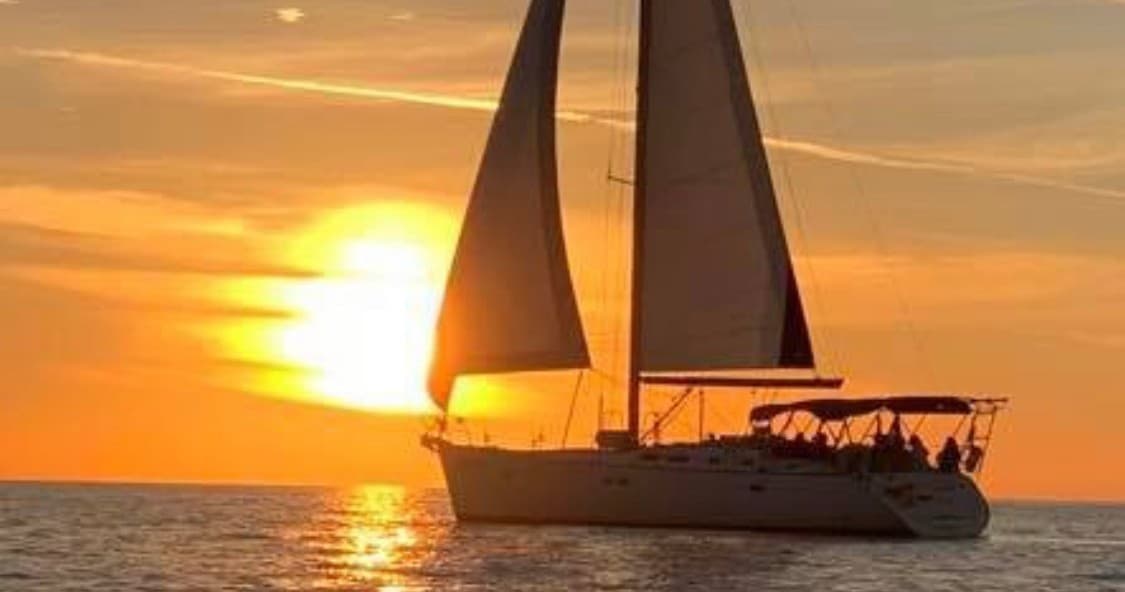 Sailboat silhouetted at golden sunset off Naples coast, serene cruise