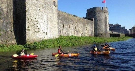 Kayakers paddling by historic stone castle on river excursion
