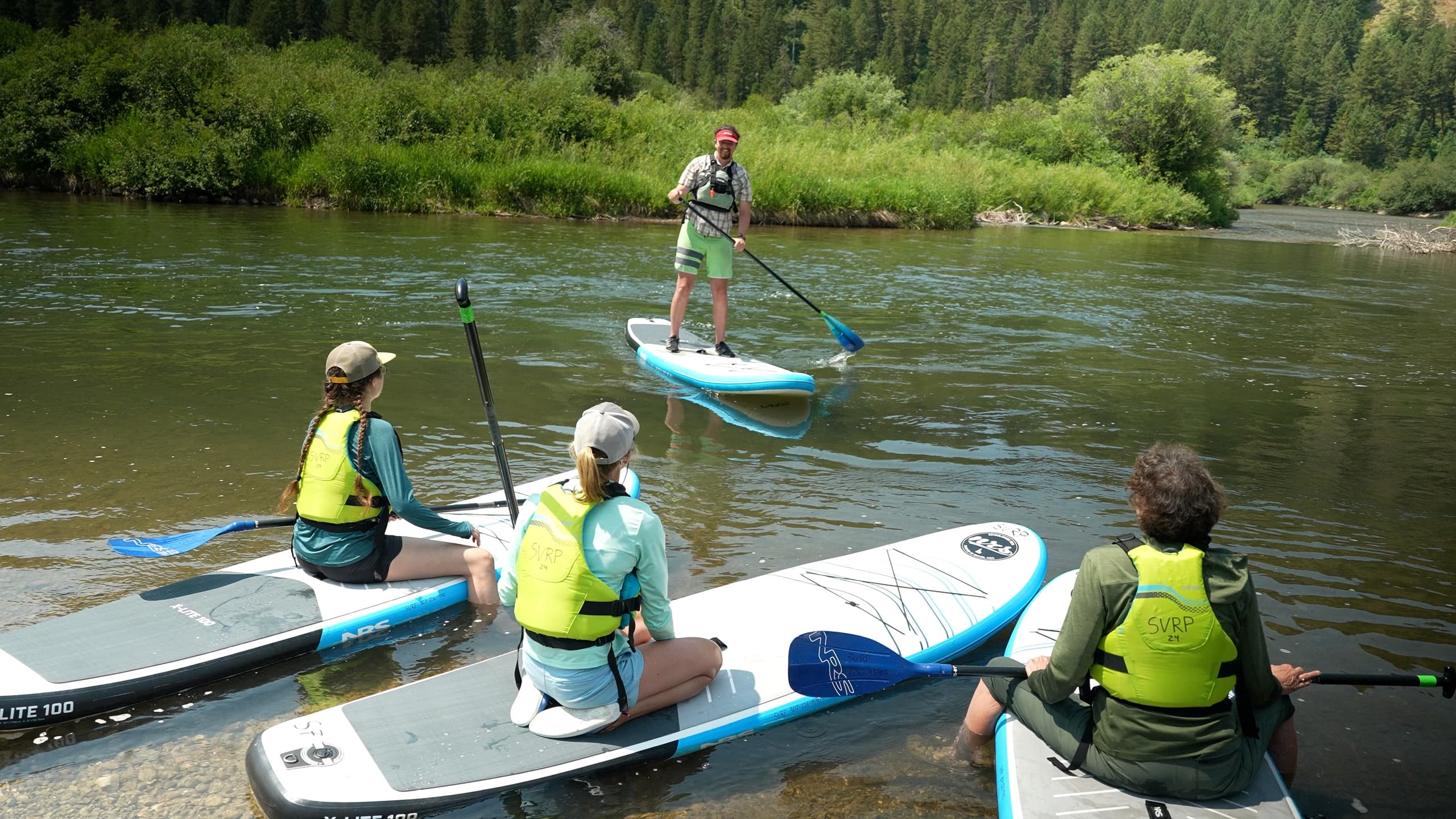Guided stand-up paddleboard lesson on calm river with instructor