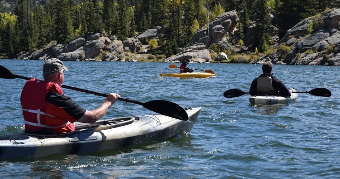 Group of kayakers touring rocky alpine lake under sun