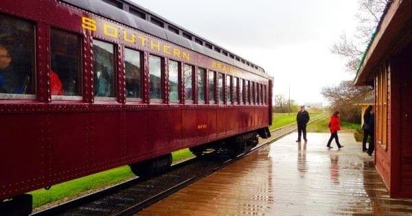 Passengers boarding vintage railcar on wet prairie station platform
