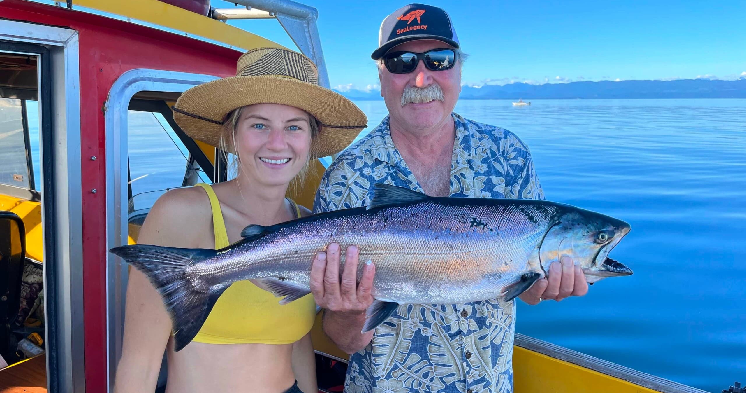 Anglers holding large salmon on blue ocean charter boat