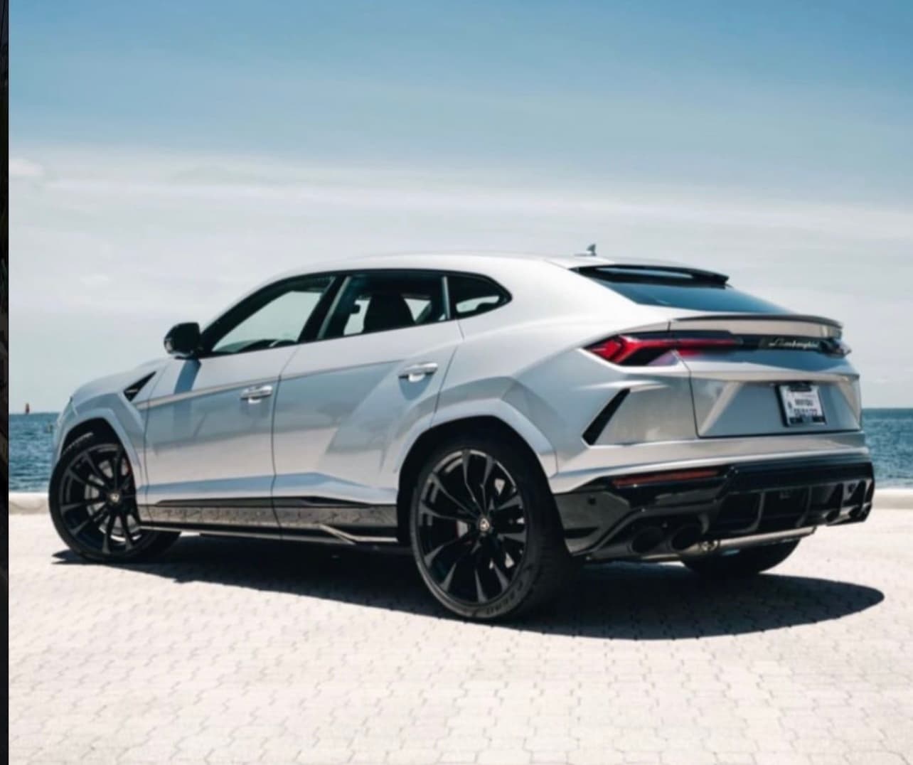 Lamborghini Urus SUV parked on sunny coastal beach road