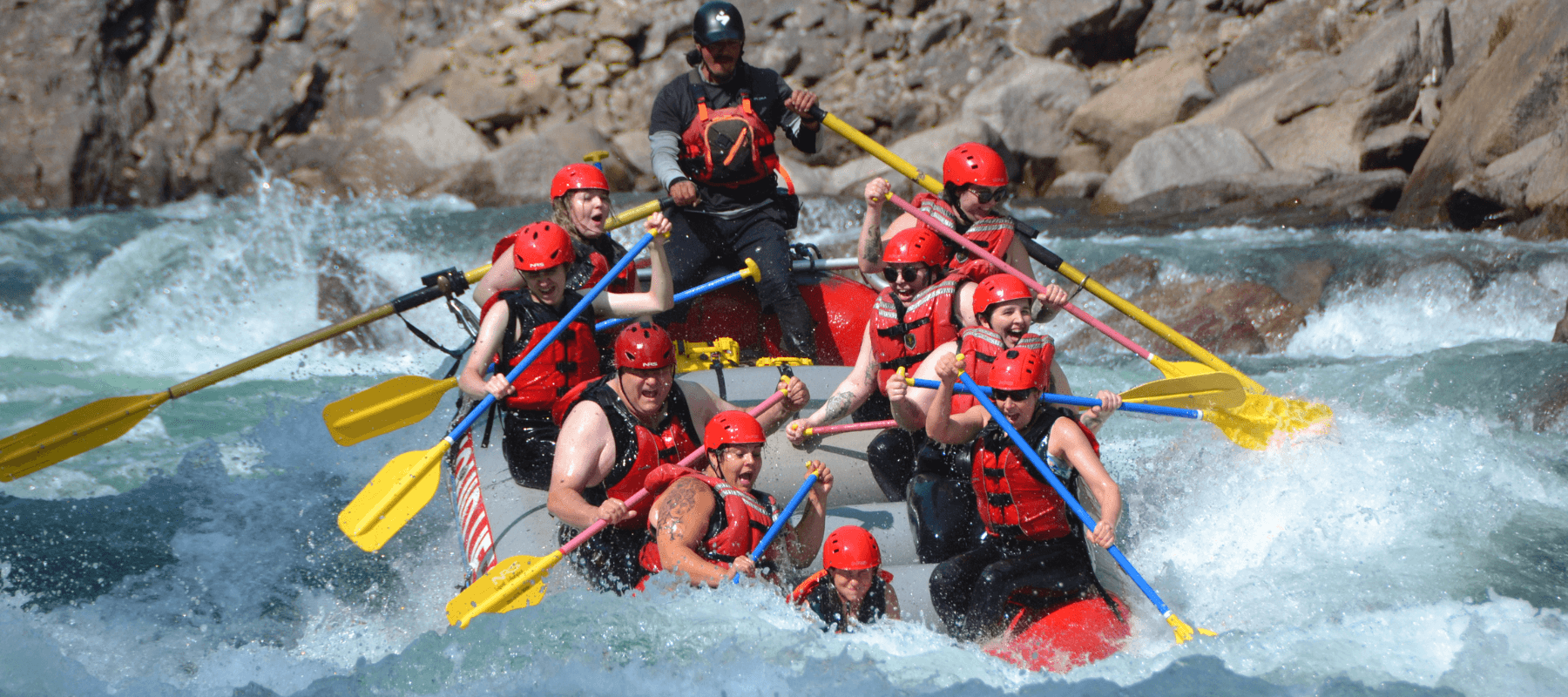 Whitewater rafting team navigating rocky canyon rapids
