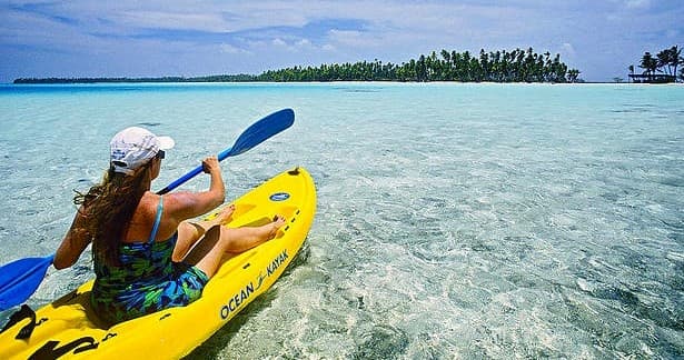 Solo kayaker paddling over crystal-clear shallow tropical lagoon