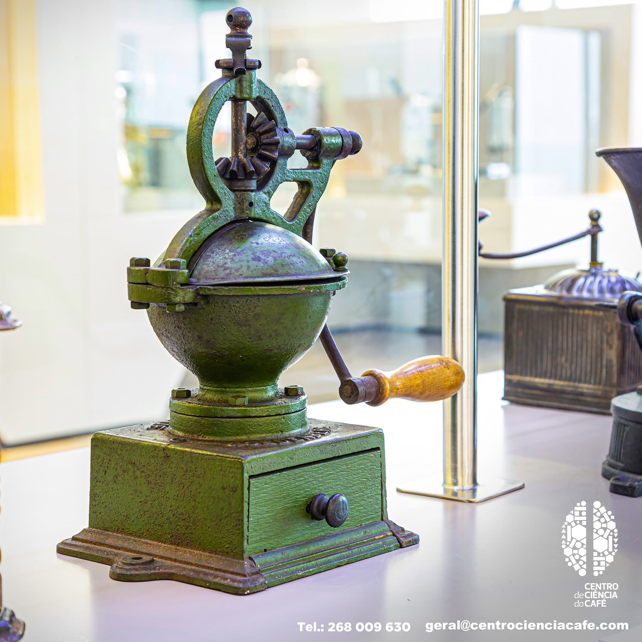 Antique coffee grinder displayed indoors in museum-style setting