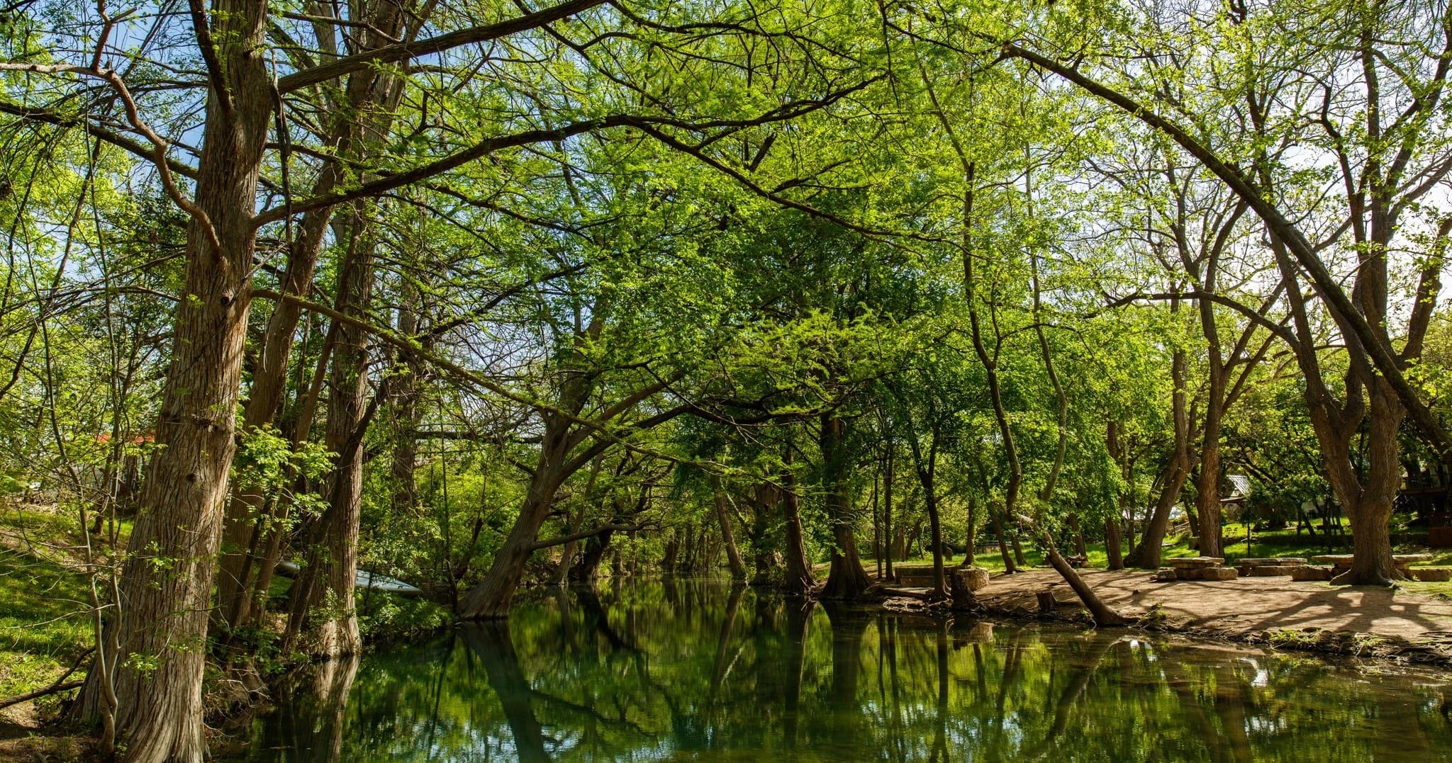 Kayak paddling on shaded Wimberley river amid green cypress trees