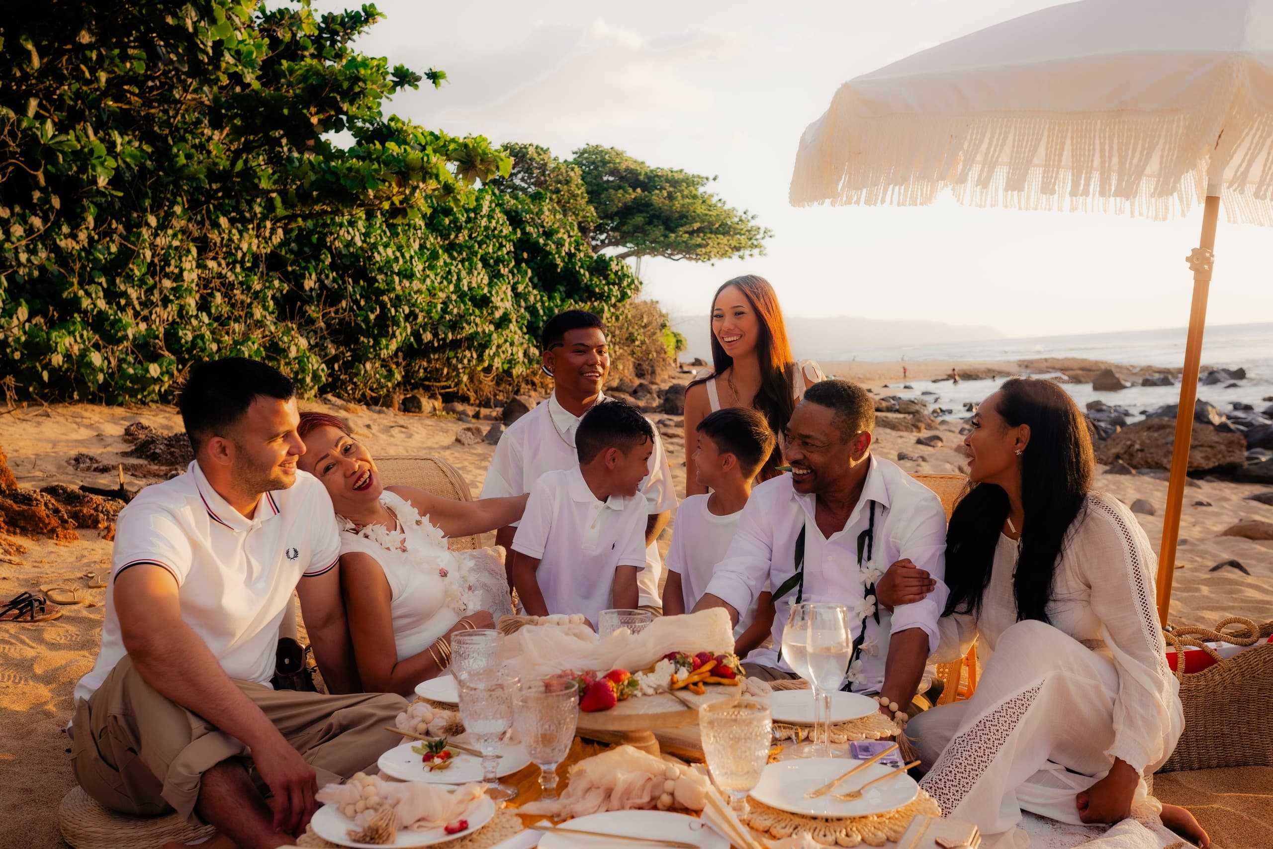 Friends enjoying sunset beach picnic with food on volcanic shore