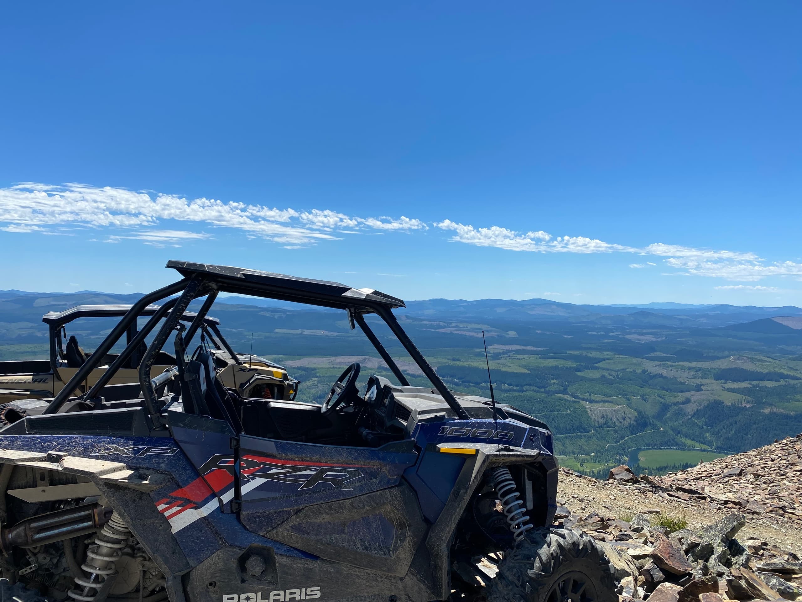 UTV parked on rocky summit with panoramic mountain vista