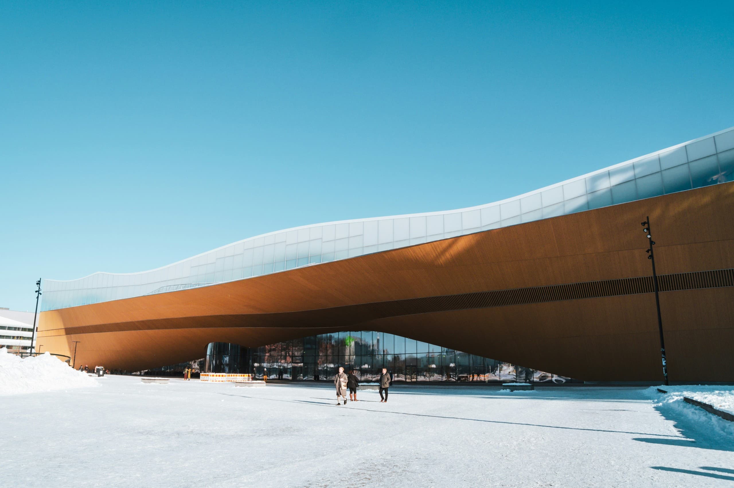 Oodi library exterior curved wooden roof in snowy daylight
