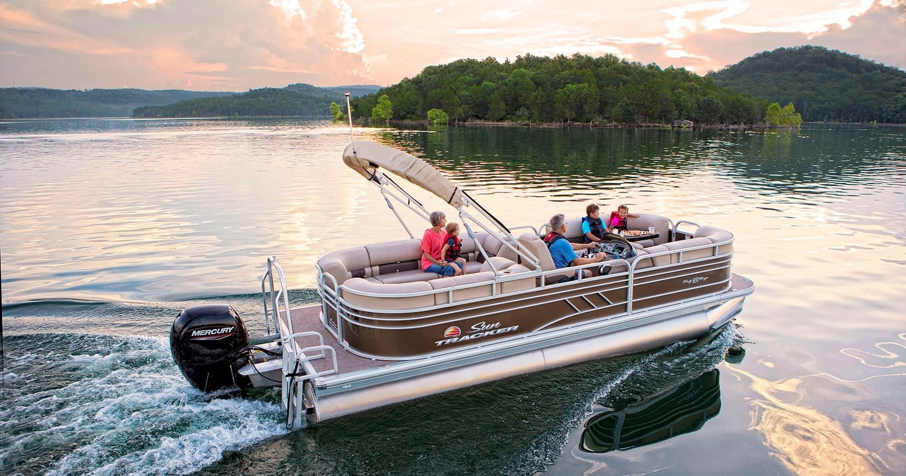 Family cruising on pontoon boat at sunset on lake