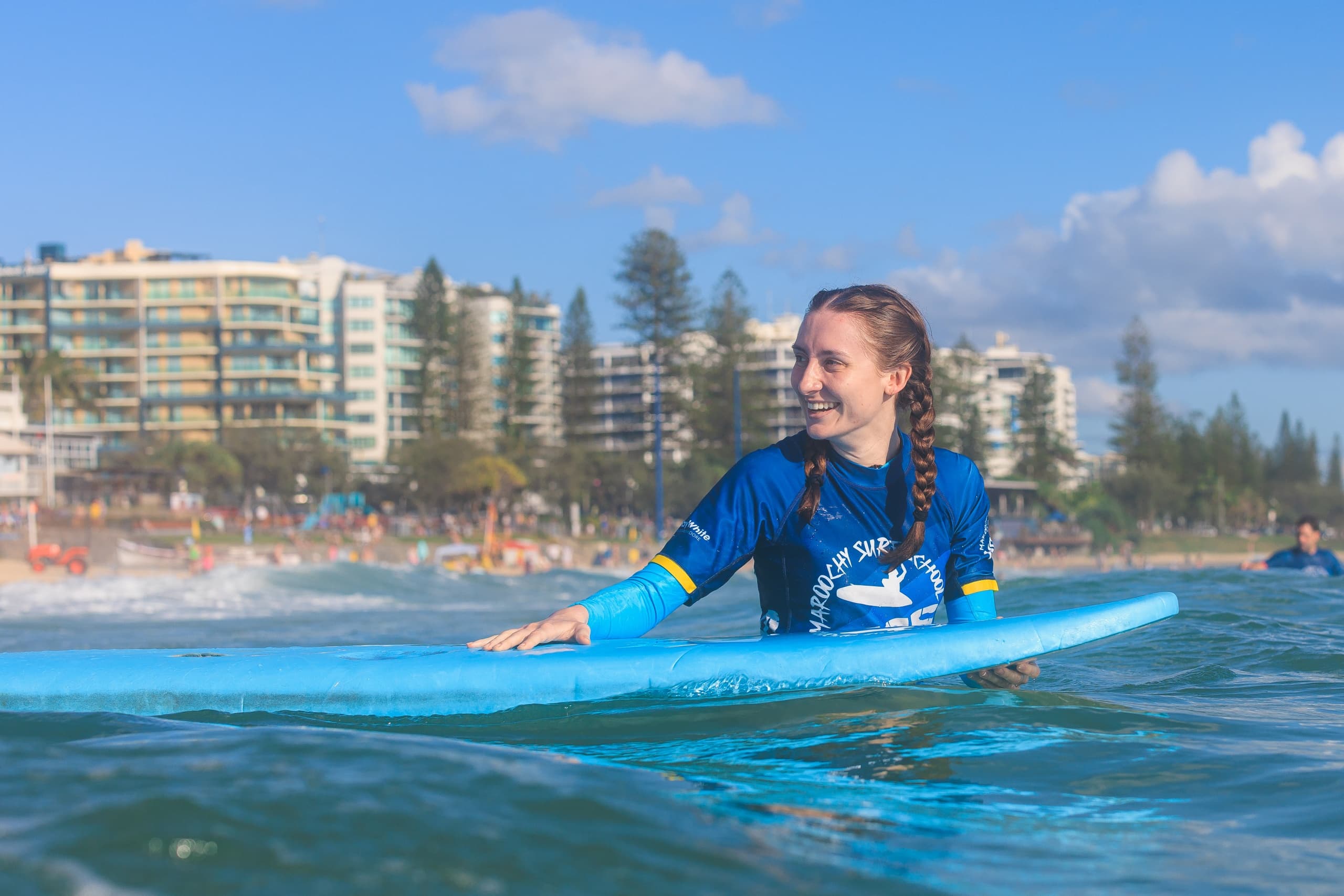 Paddling surfers catching waves near sandy beachfront