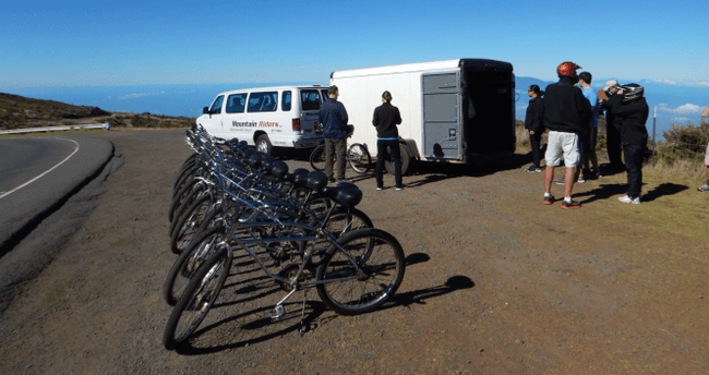 Bicycles lined by van on mountain road for guided downhill bike tour