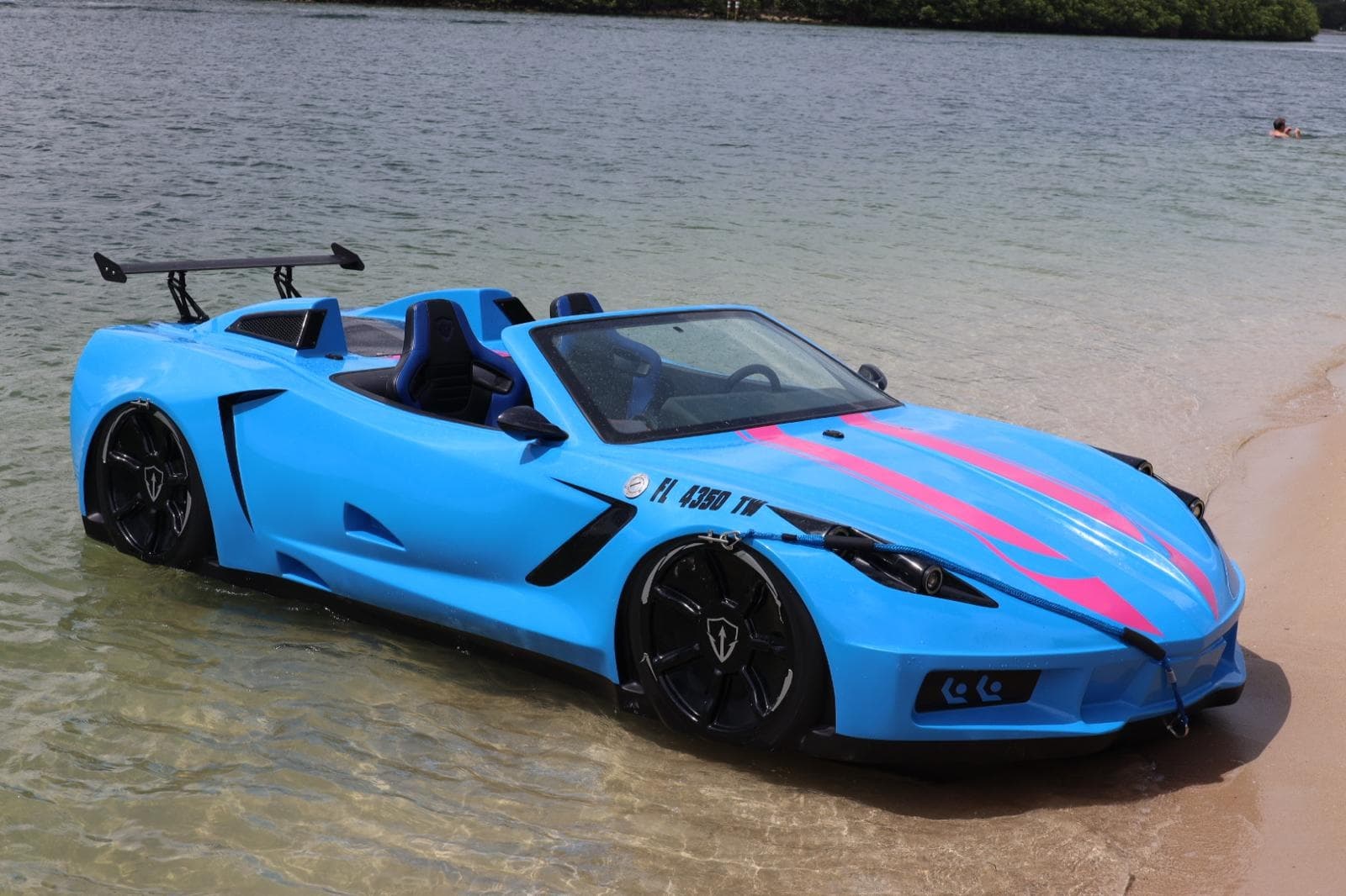 Blue convertible sports car parked on sandy beach at shoreline