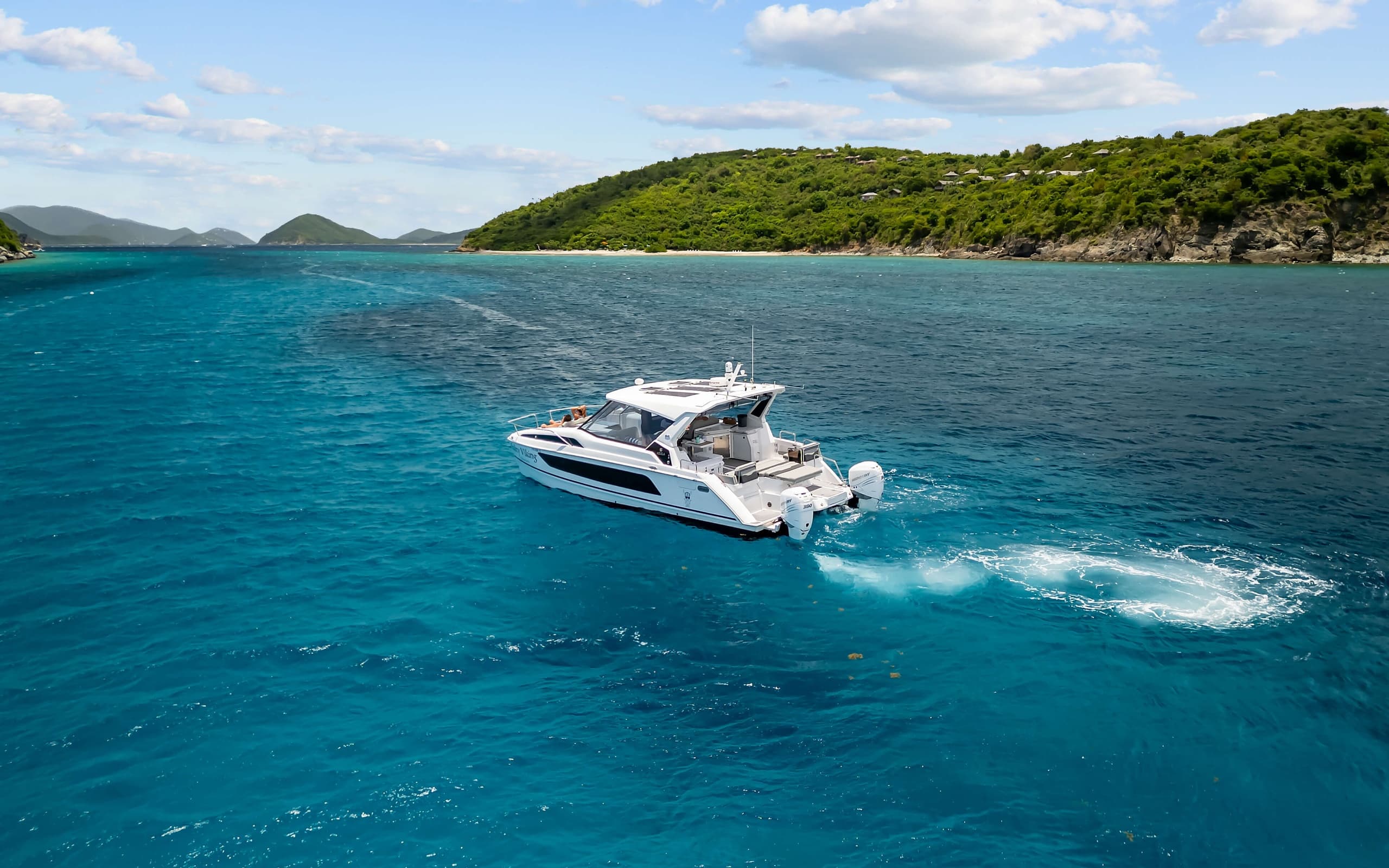 Aerial motor yacht cutting through deep blue coastal waters