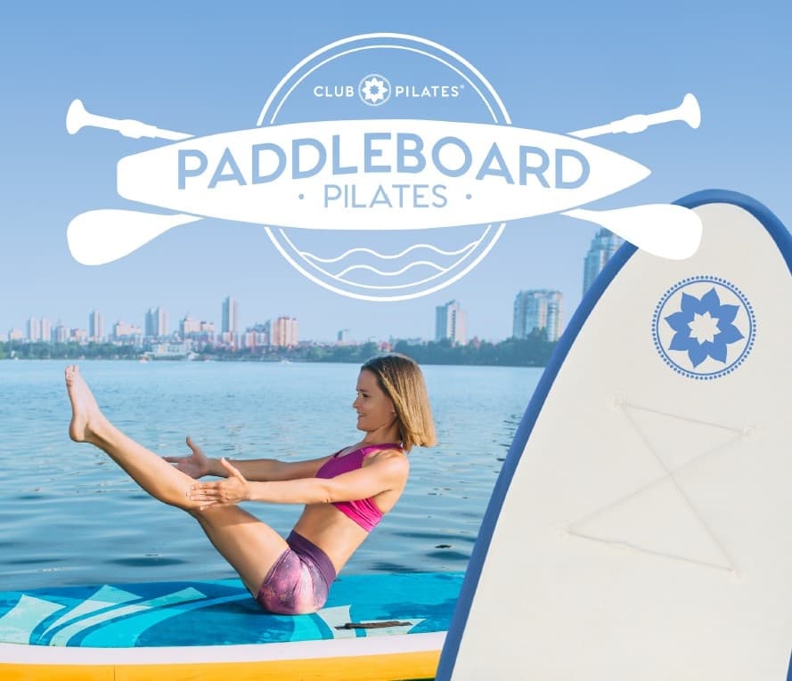 Paddleboard pilates class with instructor balancing near city skyline