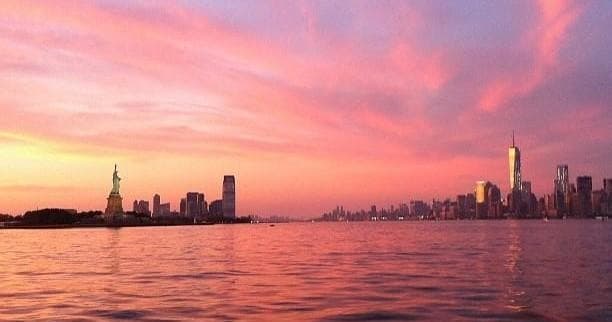 Sunset skyline with Statue of Liberty visible from boat